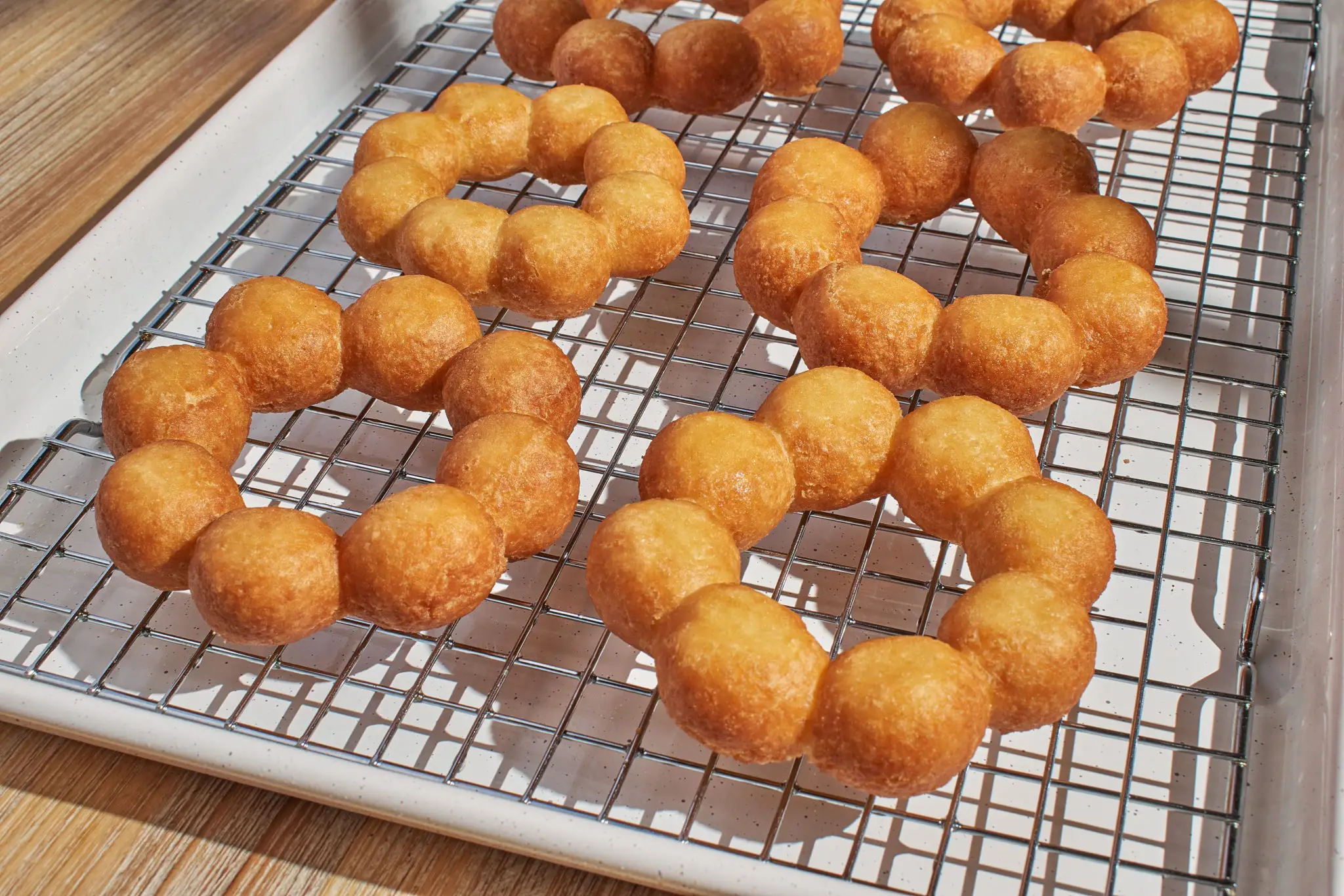 Freshly glazed mochi donuts on a cooling rack